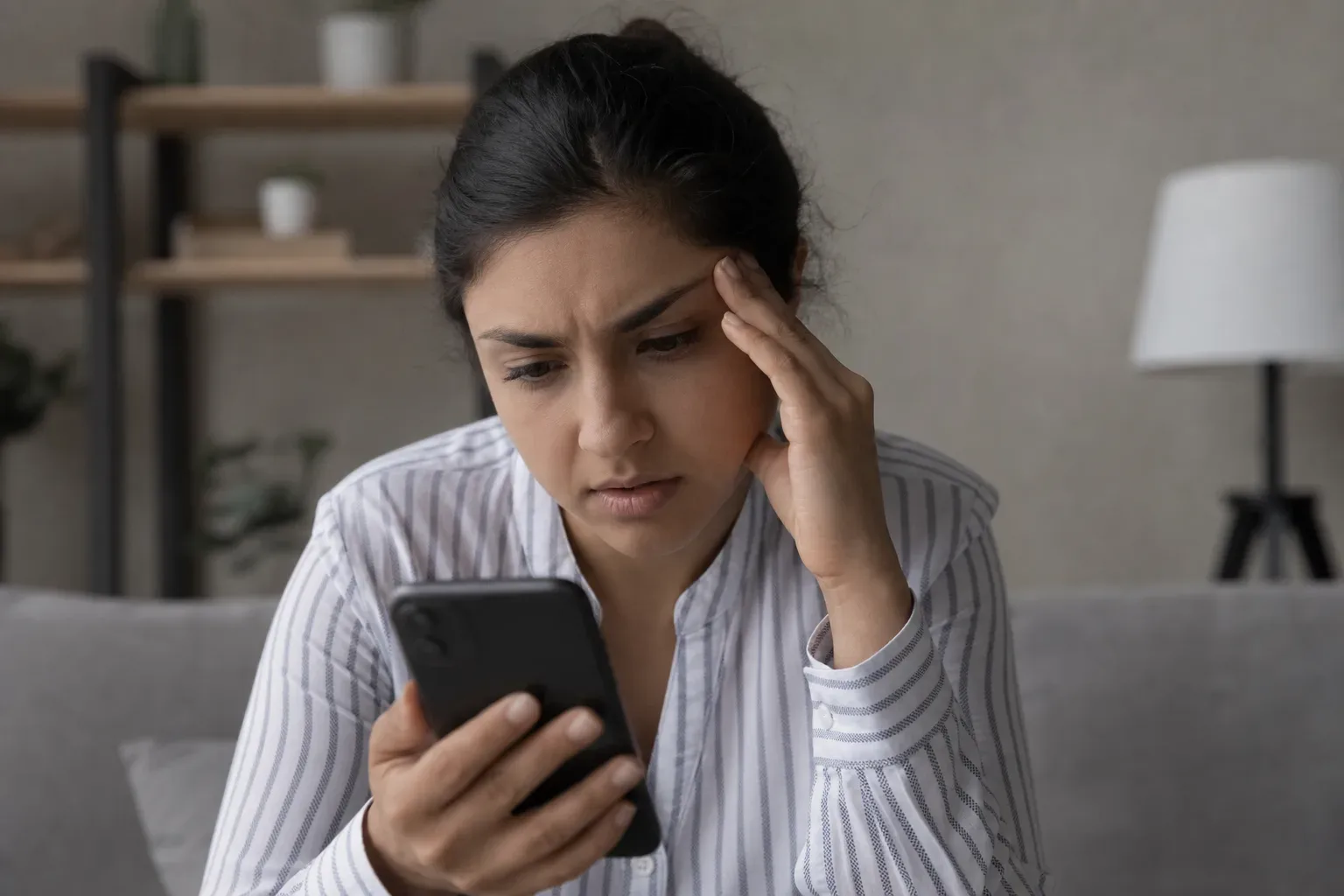 A person reading a loan rejection notification on a phone screen with a concerned expression