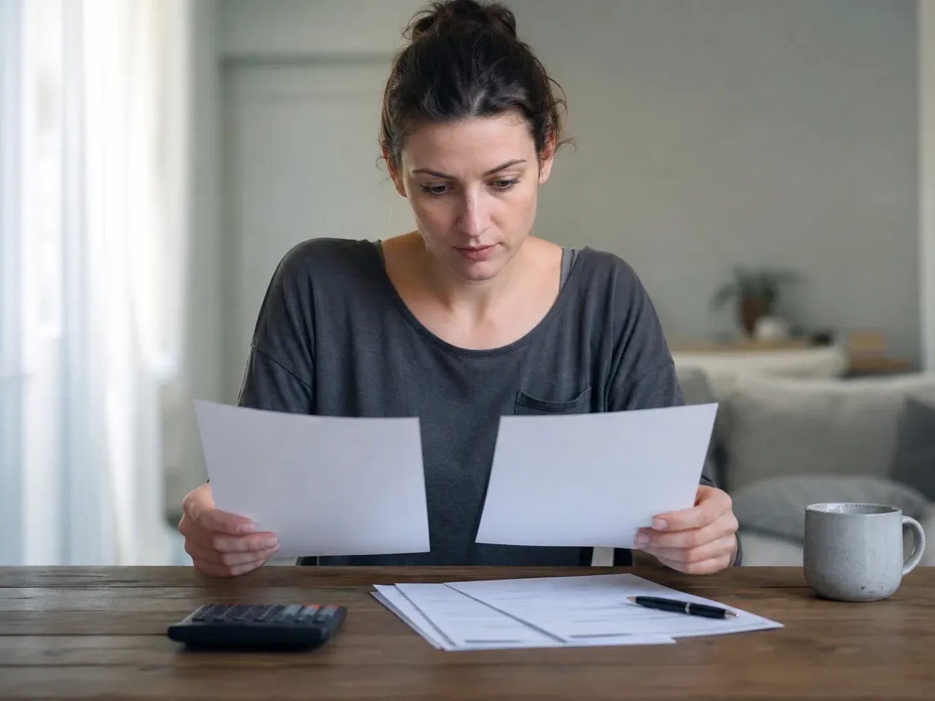 A person comparing two printed loan offer sheets side by side on a table